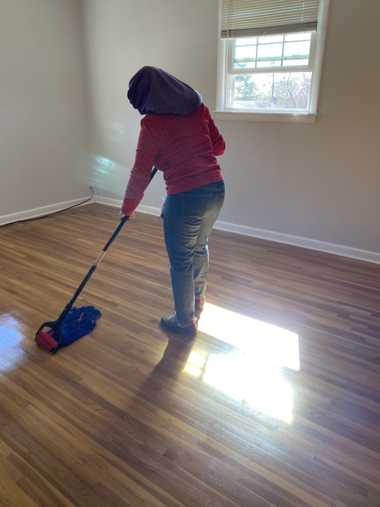 A professional house cleaner mopping a wooden floor, making it shine, by J&RD Cleaning Service LLC in Bowie, MD.