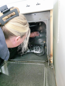 A professional house cleaner thoroughly scrubbing the inside of an oven for Clemons Cleaning service LLC in Jackson, MI.