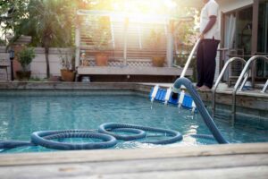 A professional performing pool vacuuming and cleaning services for a client in Henderson, NV, by Purpose Pools.