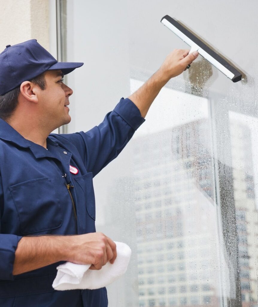 A professional cleaner meticulously cleaning a window with a squeegee, provided by Blue Line Cleaning Services in Rock Hill, SC.