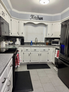 A wide view of a professionally cleaned kitchen with white cabinets and dark appliances by BNB Cleaning Pros in Hastings, NE.