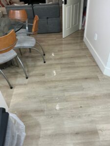 Puddles of water visible on a laminate floor in a residential dining area, indicating water damage, by PuroClean of Hilton Head in Bluffton, SC.
