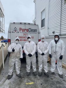 PuroClean technicians in hazmat suits standing by their van, ready for a restoration job in Nottingham, NH.