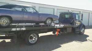 A purple classic muscle car being transported on a flatbed tow truck by Idaho State Towing and Recovery in Caldwell, ID.