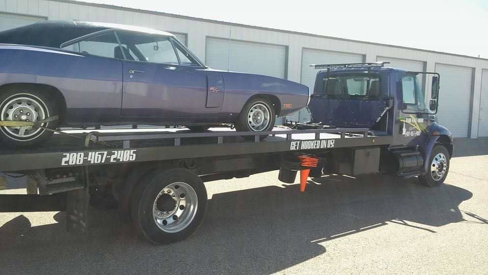 A purple classic muscle car being transported on a flatbed tow truck by Idaho State Towing and Recovery in Caldwell, ID.