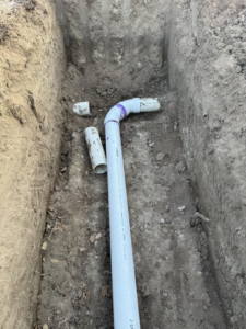 White PVC pipes laid in a trench for plumbing or drainage by MP-X LLC Excavation and Construction in Riverton, WY