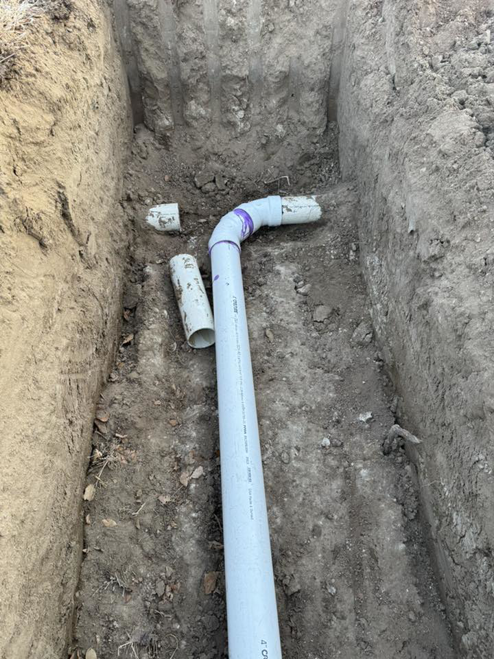 White PVC pipes laid in a trench for plumbing or drainage by MP-X LLC Excavation and Construction in Riverton, WY