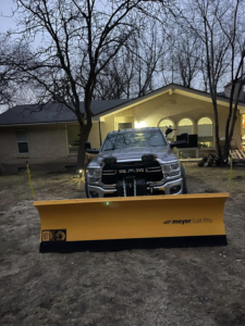 A silver RAM truck with a yellow Meyer Lot Pro snow plow, ready for snow removal by Medina's Landscape Care LLC in Layton, UT.