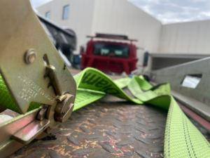 A heavy-duty ratchet strap securing a vehicle on a flatbed tow truck for Mr.Quickpick Roadside Assistance in Indianapolis, IN.