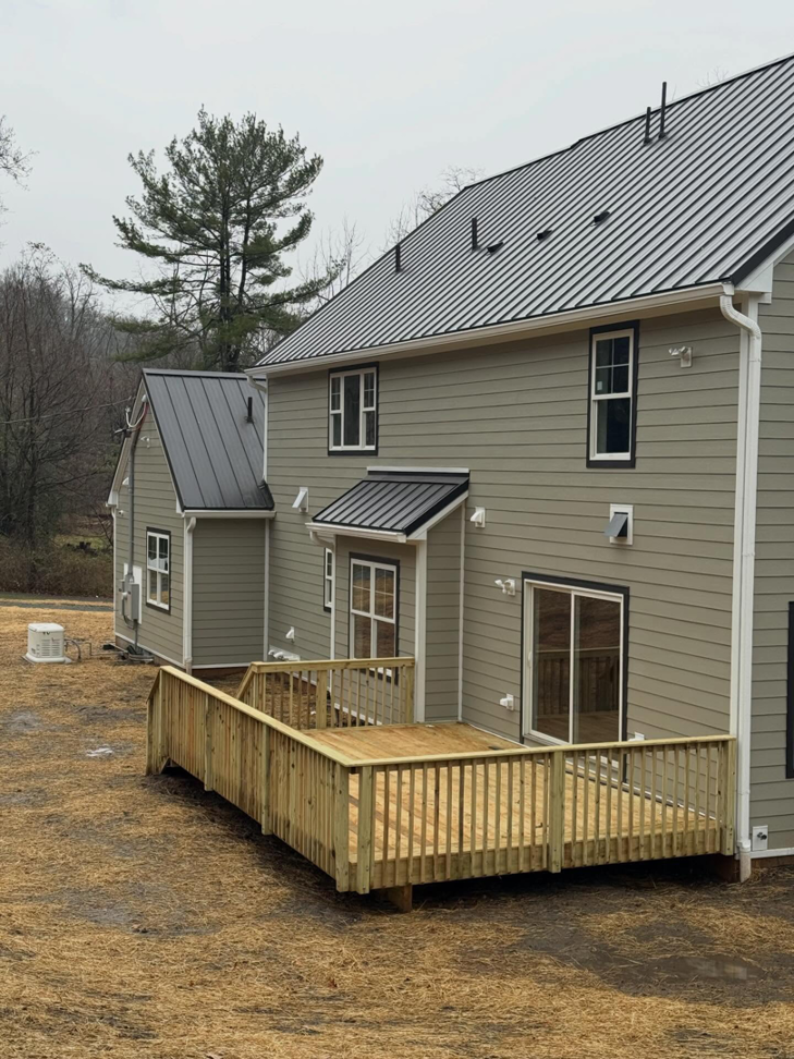 Rear view of a house with newly installed light green siding and a fresh wooden deck by CRD Builders in Hamilton Township, NJ.