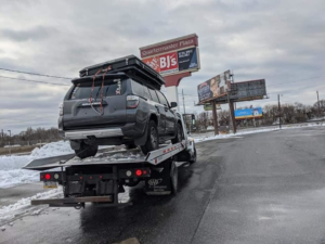 Rear view of a Kourouma Towing Services flatbed tow truck transporting an SUV near Quartermaster Plaza in Philadelphia, PA.