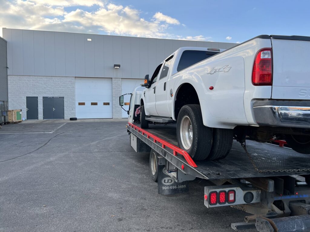 A rear view of a white Ford F-350 dually pickup truck on a tow truck from Anytime towing services in Columbus, OH.