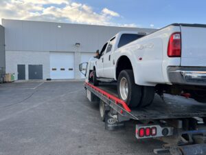 A rear view of a white Ford F-350 dually pickup truck on a tow truck from Anytime towing services in Columbus, OH.