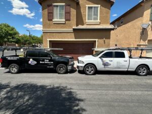 Two Rebel Overhead Doors service trucks parked in front of a house, ready for a garage door job in Las Vegas, NV.