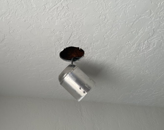 A recessed light fixture falling from a water-damaged ceiling, indicating structural issues addressed by RestoPros of Salt Lake City, UT