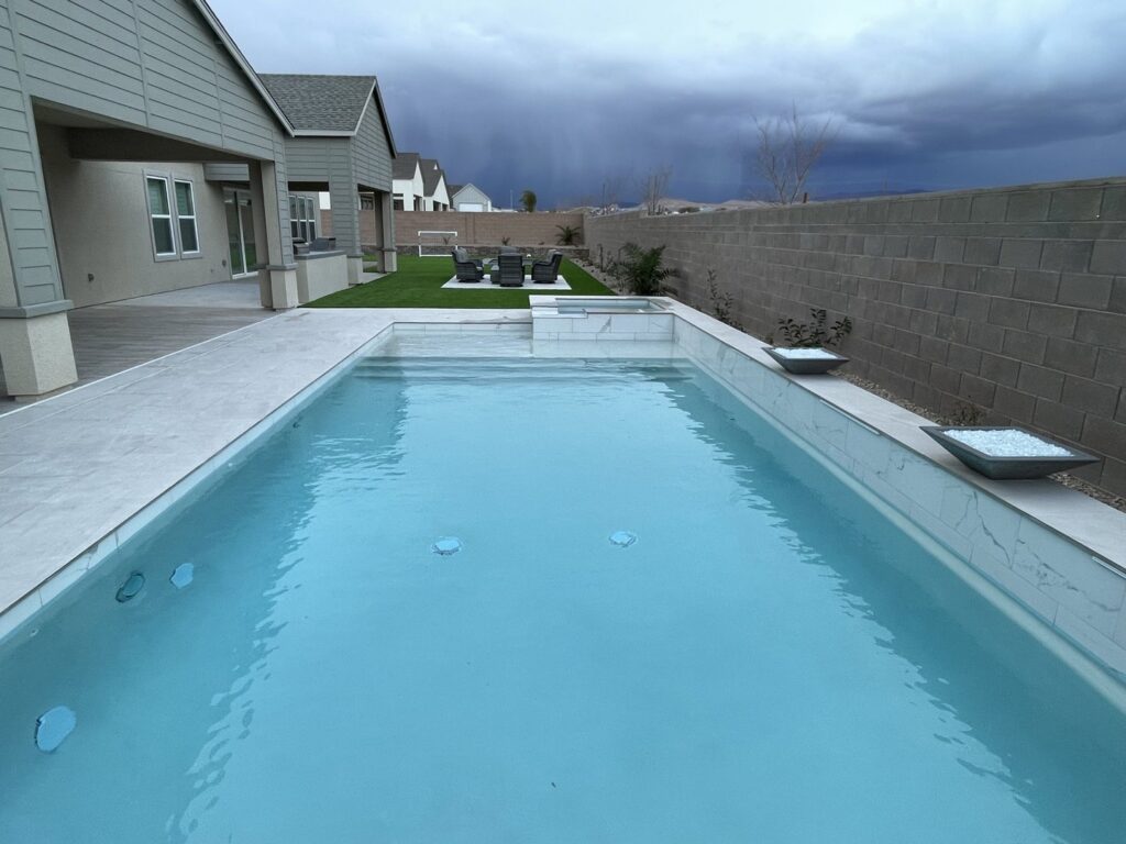 A rectangular pool with a raised spa and contemporary landscaping, designed by Steve Breck Pools in Las Vegas, NV.