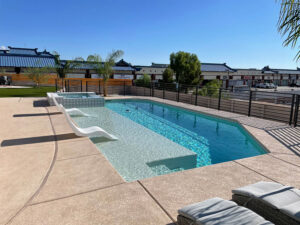 A rectangular pool with a sun shelf and lounge chairs, suitable for commercial or residential use, by Steve Breck Pools in Las Vegas, NV.