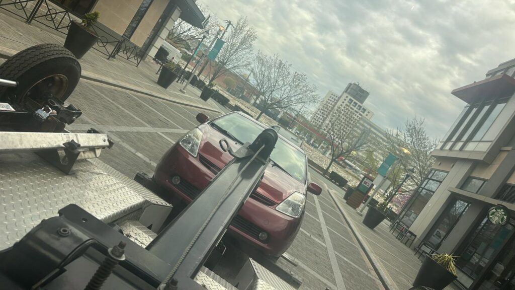 A red car being prepared for towing on a flatbed tow truck, providing service by Ricky's Towing & Recovery LLC in Derwood, MD.