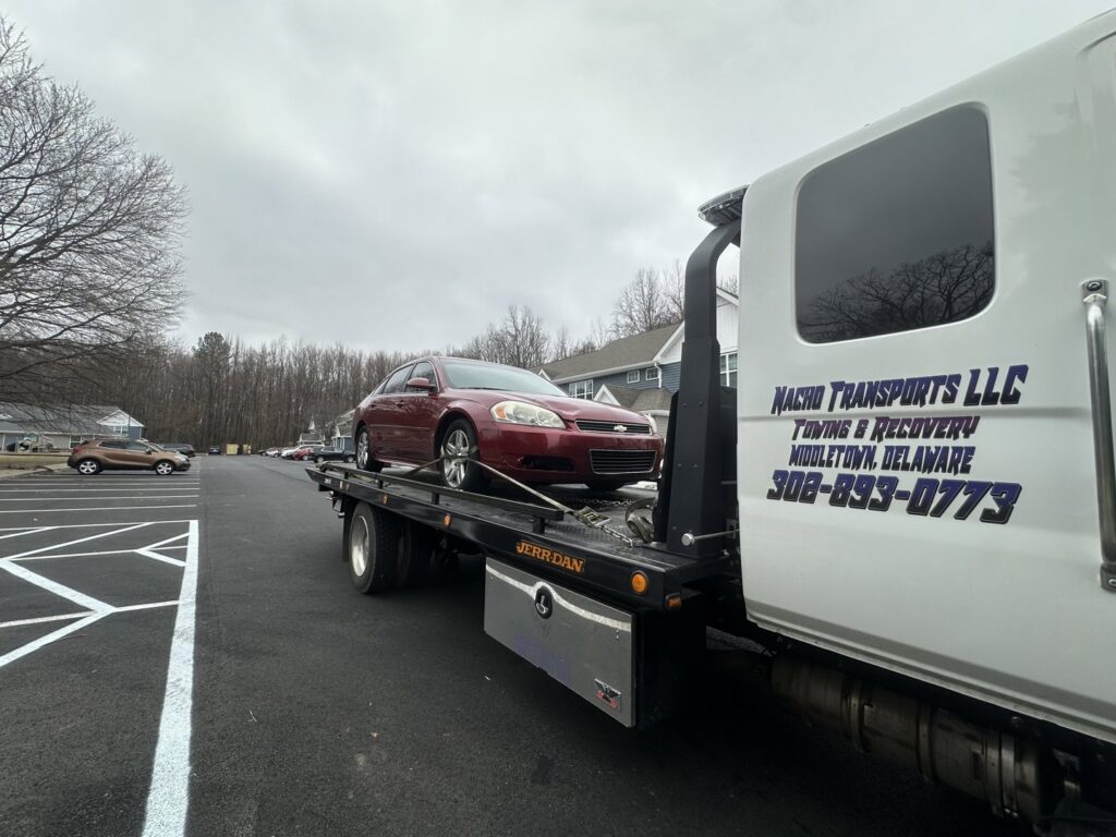 A red car loaded onto a flatbed tow truck from Nacho Transports llc in Middletown, DE.
