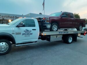 A red Chevrolet Silverado pickup truck being transported on a flatbed tow truck by Grace to Grace Towing in Atlanta, GA.