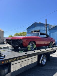 A red classic car is secured on a flatbed tow truck by S&F Towing in Oakland, CA.