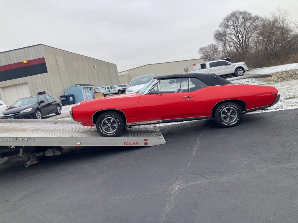 A red classic convertible car being towed on a flatbed truck by Towing Recovery Rebuilding Assistance Services in Naperville, IL