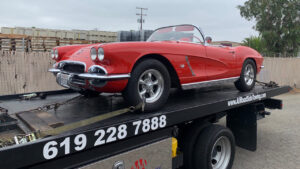 A red classic Corvette being transported on a flatbed tow truck by All Roadside Towing San Diego, CA.