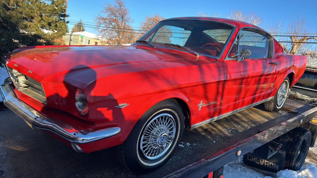 A red classic Mustang being transported on a flatbed tow truck by A-ROD Towing in Denver, CO.