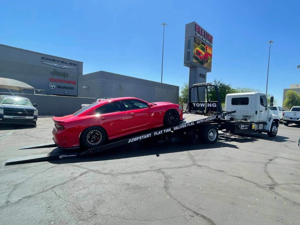 A red Dodge Charger sedan loaded onto a flatbed tow truck by Rojo's Towing in Phoenix, AZ.