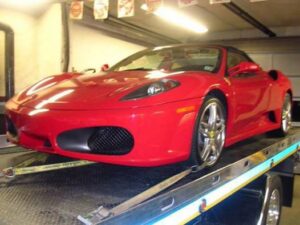 A red Ferrari being transported on a flatbed tow truck by Towing Recovery Rebuilding Assistance Services in Naperville, IL