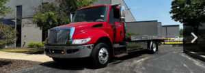 A bright red flatbed tow truck parked outside for Morris Trucking LLC in Indianapolis, IN.