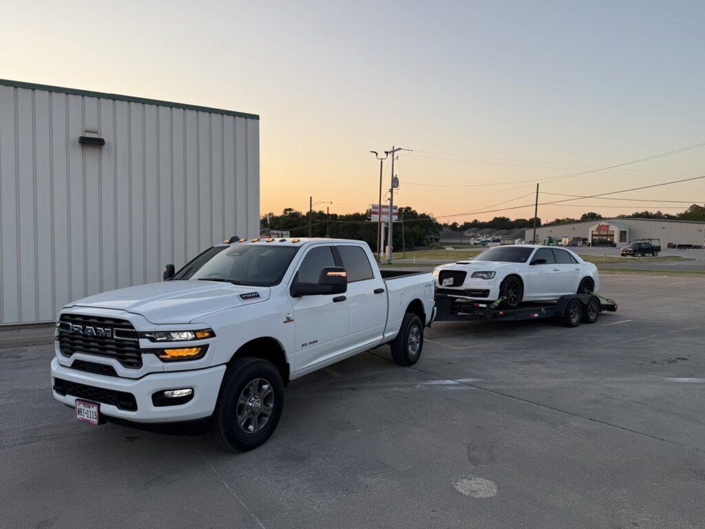 A red flatbed tow truck transporting a red pickup truck at night for RDZ Towing Service 24/7 in Dallas, TX.
