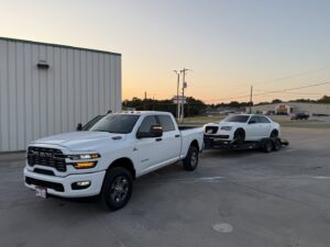 A red flatbed tow truck transporting a red pickup truck at night for RDZ Towing Service 24/7 in Dallas, TX.