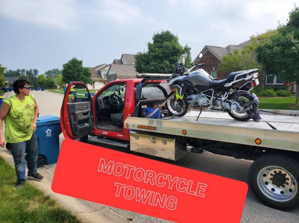 A red flatbed tow truck with a motorcycle loaded for transport, offering motorcycle towing services by JR's Services and Recovery, LLC in Indianapolis, IN.