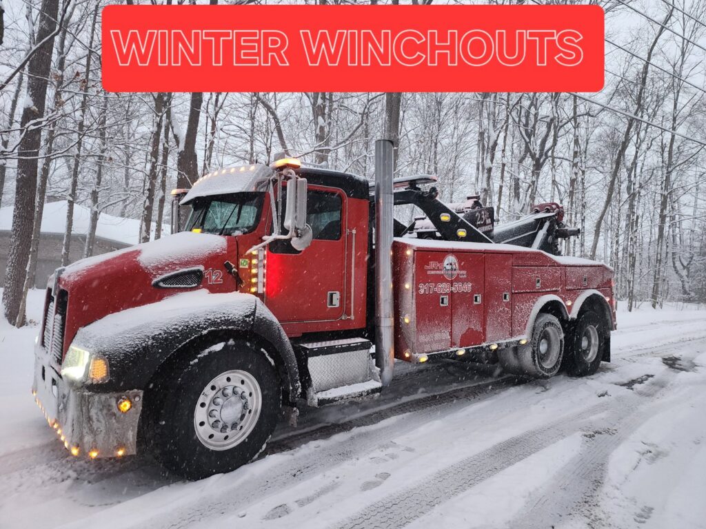 A red heavy-duty tow truck in a snowy landscape, ready for winter winch-outs and recovery services by JR's Services and Recovery, LLC in Indianapolis, IN.