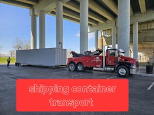 A red heavy-duty tow truck transporting a large shipping container on a trailer, offering specialized transport by JR's Services and Recovery, LLC in Indianapolis, IN.
