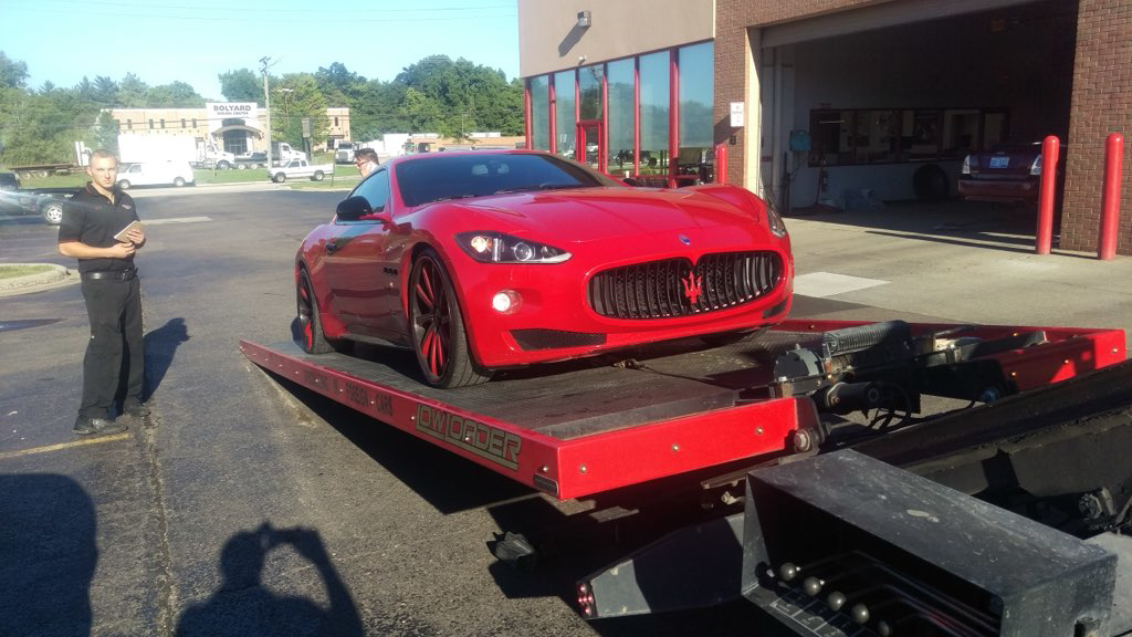 A red Maserati sports car being loaded onto a flatbed tow truck by Triple D's Towing in Sterling Heights, MI.