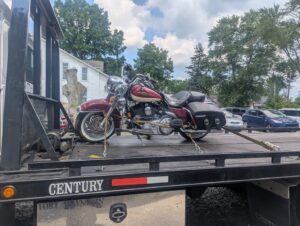 A red motorcycle being transported on a flatbed tow truck by First Hand Towing & Recovery in Fort Wayne, IN.