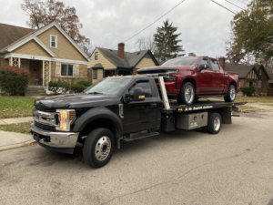 A red pickup truck transported on a flatbed tow truck by Triple T's Tow, Tire, & Transportation in Cincinnati, OH.