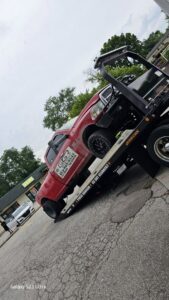A red pickup truck being transported on a flatbed tow truck by Vatos Locos Towing in Cincinnati, OH.