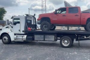 A red pickup truck loaded onto a flatbed tow truck from Wilkerson's Towing & Automotive LLC in Bowling Green, KY.