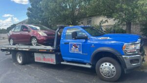 A red Toyota Prius being transported on a flatbed tow truck by Vatos Locos Towing in Cincinnati, OH.
