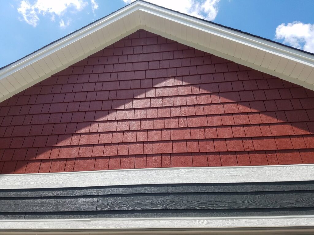 Close-up of a house gable featuring red shake siding above dark gray horizontal siding by Triton Exteriors in Maple Grove, MN.