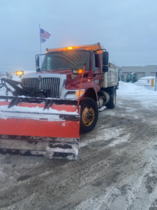 A red snow plow truck with an American flag, ready for snow removal services by Greenscape USA, Inc. in Parma, OH.