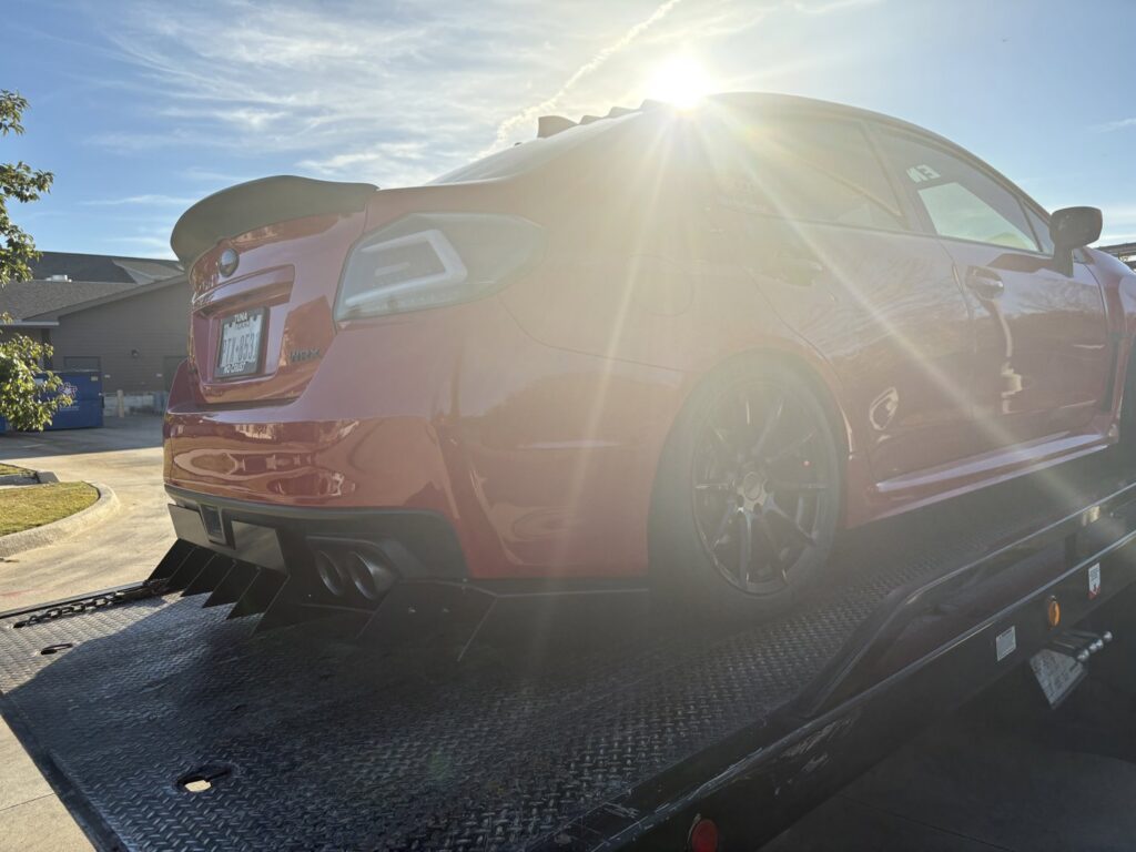A red sports car being transported on a Tow Jam flatbed tow truck in Dallas, TX.