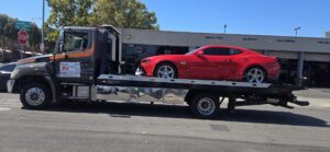 A red sports car being towed on a flatbed tow truck by Ibanez Towing Service LLC in San Jose, CA.