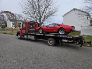 A red sports car being towed on a flatbed truck by Riggleman Towing in Moorefield, WV.