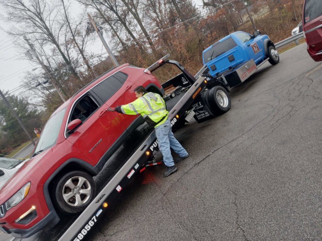 A red SUV being loaded onto a flatbed tow truck by a Vatos Locos Towing employee in Cincinnati, OH.