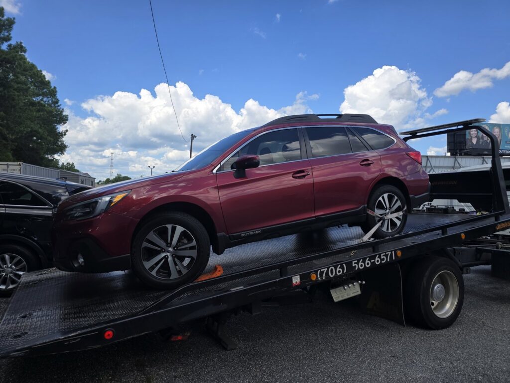 A red SUV being towed on a flatbed truck by Advance Towing & Recovery in Columbus, GA.