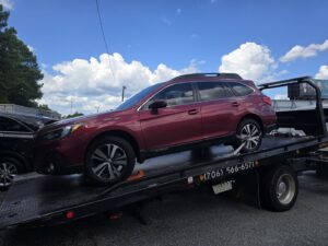 A red SUV being towed on a flatbed truck by Advance Towing & Recovery in Columbus, GA.